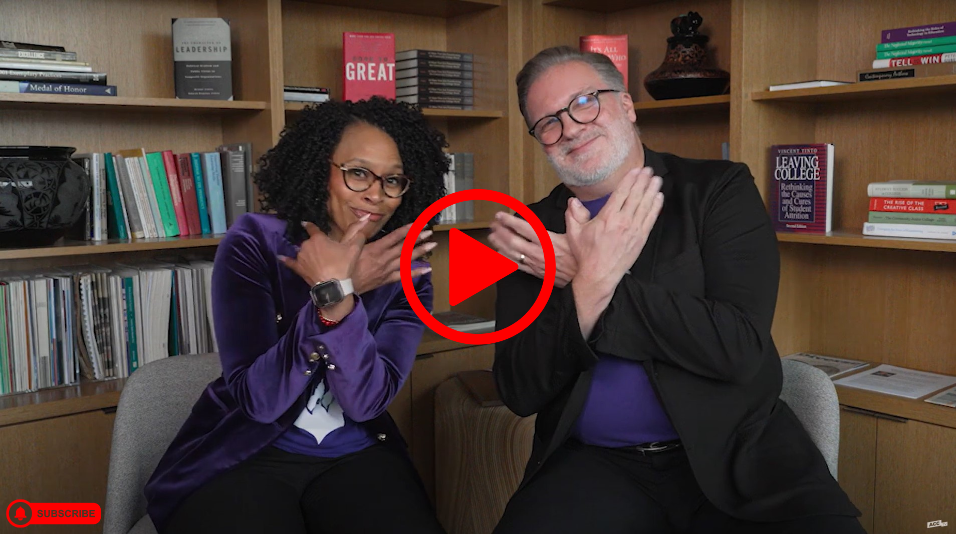 Miriam Smith and Russell Lowery-Hart making ACC Riverbat hand gesture with video play button overlay and subscribe overlay on bottom corner